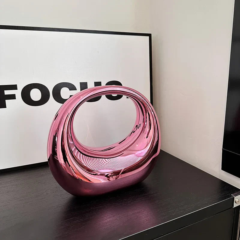 Scultura moderna in vetro rosa su mensola nera, design astratto, decorazione d'interni elegante, accanto a quadro con scritta "FOCUS".