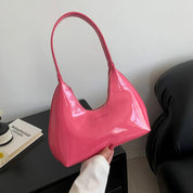 Borsa a spalla rosa lucida, design moderno, manico singolo, su sfondo neutro. Accessorio moda elegante, perfetto per look casual e chic.