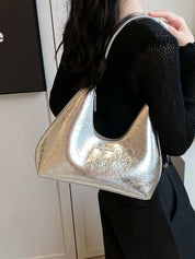 Borsa a spalla argento metallizzato, design moderno, indossata da donna in abbigliamento nero. Accessorio moda elegante e trendy.