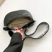Borsa a tracolla nera in pelle con cerniera aperta, interno beige, cinturino intrecciato bianco e nero, moda donna, accessorio elegante.