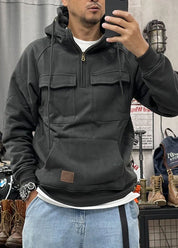 Uomo con felpa nera con cappuccio e tasche frontali, jeans chiari, orologio al polso, scatta selfie in negozio di abbigliamento casual.