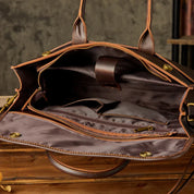 Borsa in pelle marrone aperta con scomparti interni, cerniere e manici. Design elegante e spazioso, ideale per lavoro e viaggi.