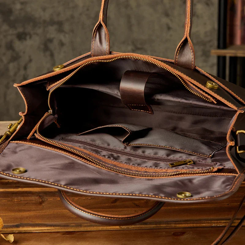 Borsa in pelle marrone aperta con scomparti interni, cerniere e manici. Design elegante e spazioso, ideale per lavoro e viaggi.