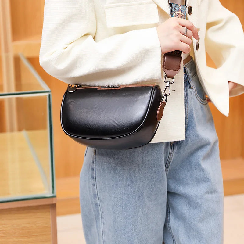 Borsa a tracolla nera in pelle, indossata su giacca bianca e jeans. Accessorio moda elegante, perfetto per look casual e chic.