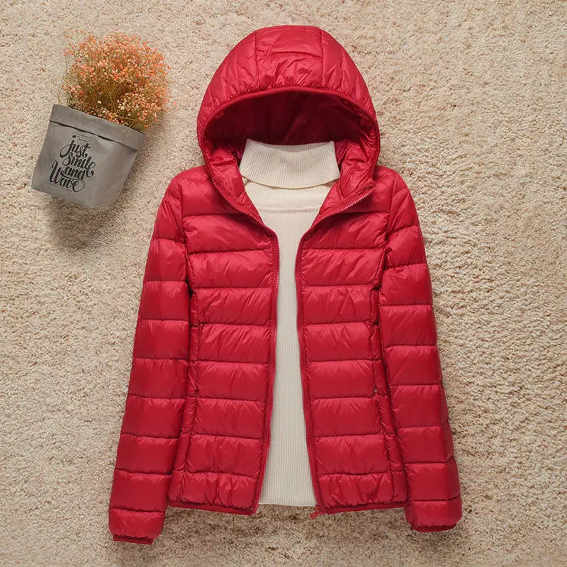 Giacca invernale donna rossa con cappuccio, imbottita, su sfondo beige. Moda femminile, abbigliamento caldo, giacca trapuntata elegante.