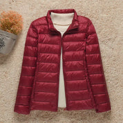 Giacca invernale trapuntata rossa da donna su sfondo beige, con collo alto e design elegante. Perfetta per moda autunno-inverno.