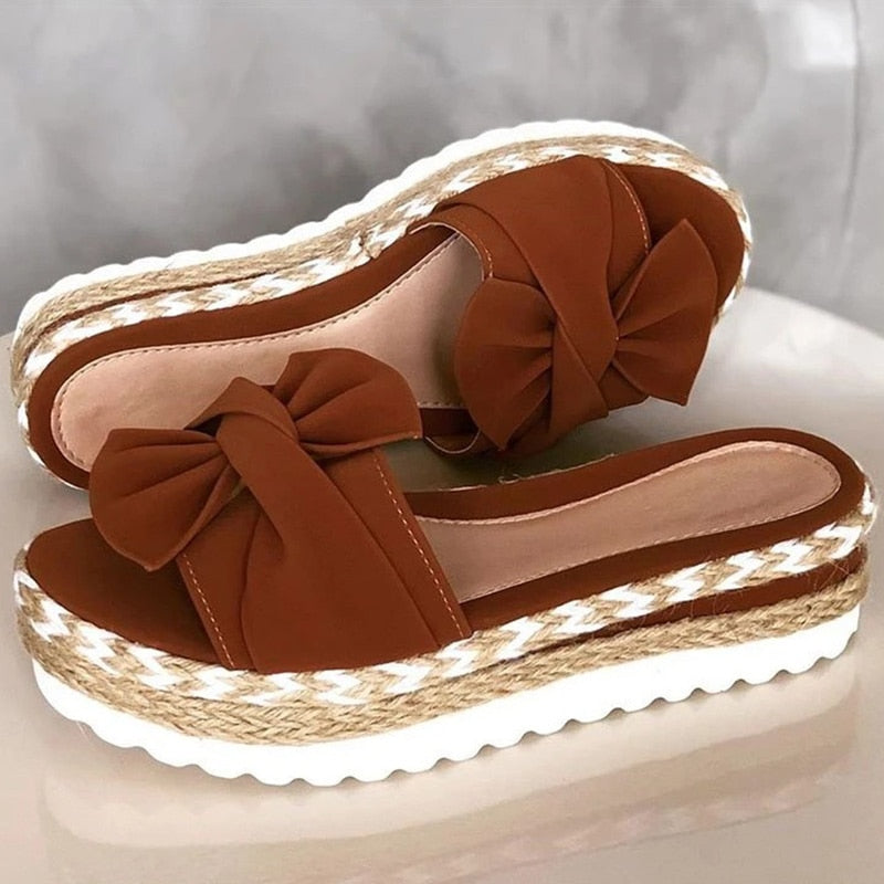 Sandali donna con zeppa in sughero, colore marrone, decorati con fiocco, suola bianca ondulata. Scarpe estive eleganti e comode.