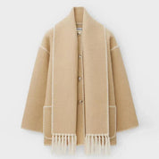 Cappotto beige in lana con frange, bottoni frontali e dettagli cuciti a contrasto. Elegante e caldo, ideale per l'inverno. Moda donna autunno inverno.