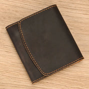 Portafoglio in pelle marrone scuro su sfondo in legno, cuciture a contrasto, design elegante e compatto, accessorio moda uomo di alta qualità.