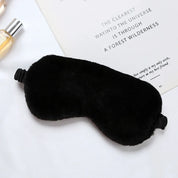 Maschera per dormire in pelliccia sintetica nera su sfondo bianco, accessorio per il sonno, comfort notturno, relax, ideale per viaggi e riposo.