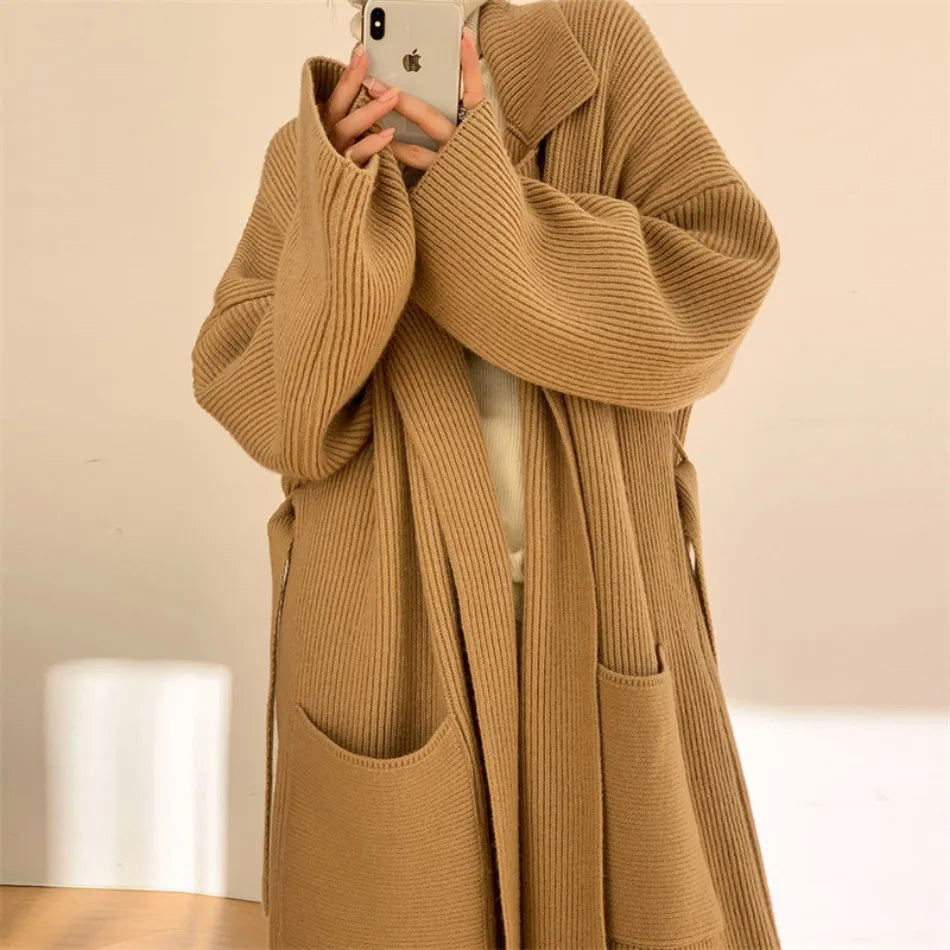 Donna con cappotto lungo in maglia beige, tasche frontali, stile casual chic, perfetto per l'autunno inverno. Fashion femminile elegante.