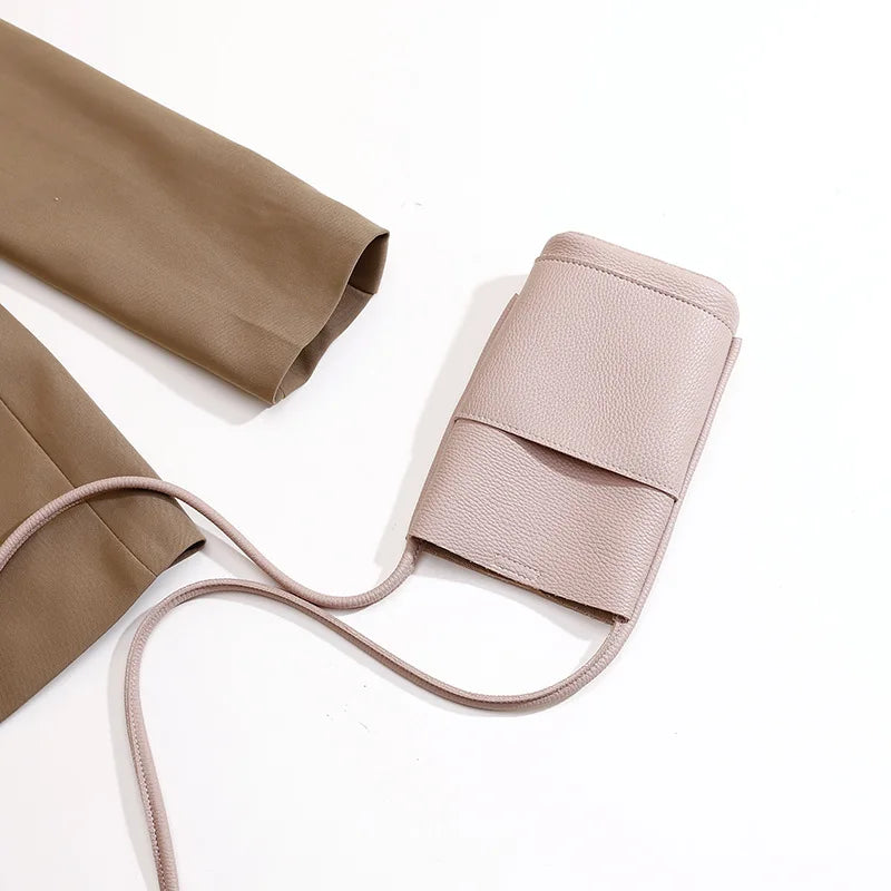 Borsa a tracolla in pelle rosa chiaro su sfondo bianco, design minimalista, ideale per smartphone, moda donna, accessorio elegante e pratico.