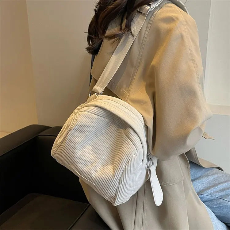 Zaino in velluto a coste beige su donna con cappotto beige, stile casual. Accessorio moda femminile, ideale per look autunnali e invernali.