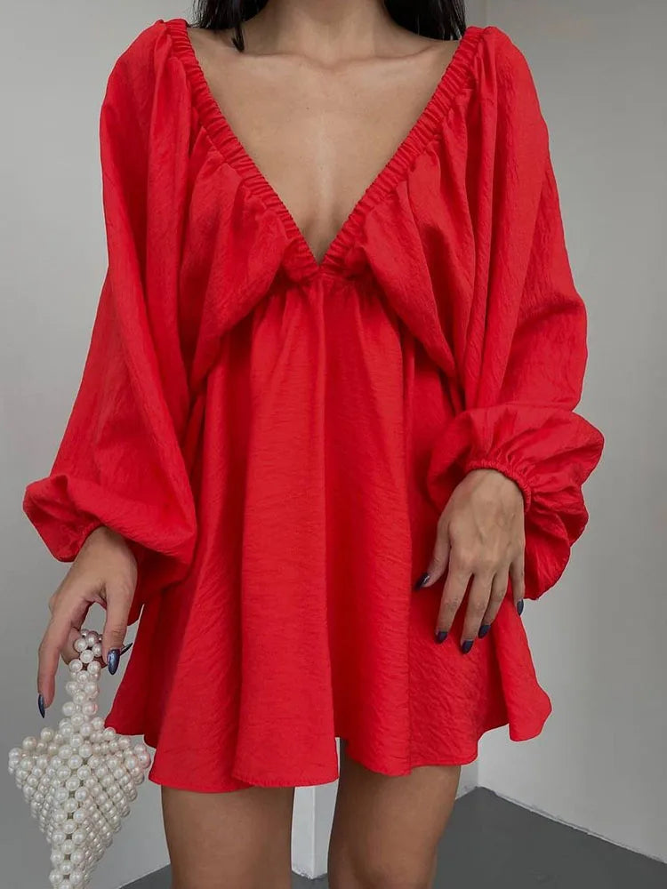 Donna con abito rosso a maniche lunghe e scollatura profonda, borsa a perline bianca. Moda femminile elegante, tendenze abbigliamento 2023.
