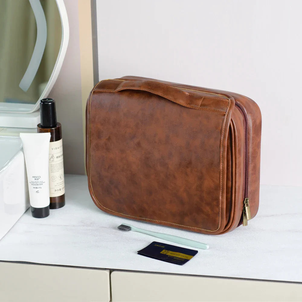 Borsa da toilette in pelle marrone su tavolo da bagno, con prodotti per la cura della pelle e specchio. Elegante e pratica per viaggi.