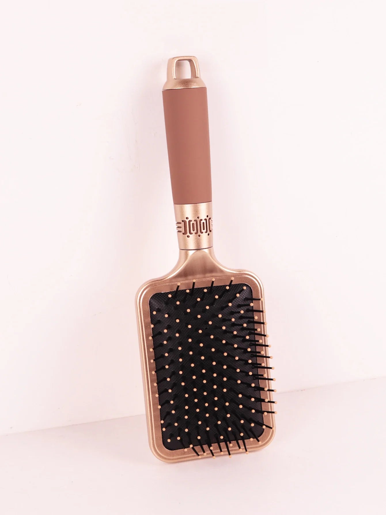 Spazzola per capelli rettangolare dorata con setole nere e manico ergonomico marrone, ideale per districare e lisciare i capelli.