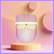 Occhiali futuristici con design a linee viola su sfondo astratto rosa e arancione, posizionati su un piedistallo di legno. Accessorio moda innovativo.
