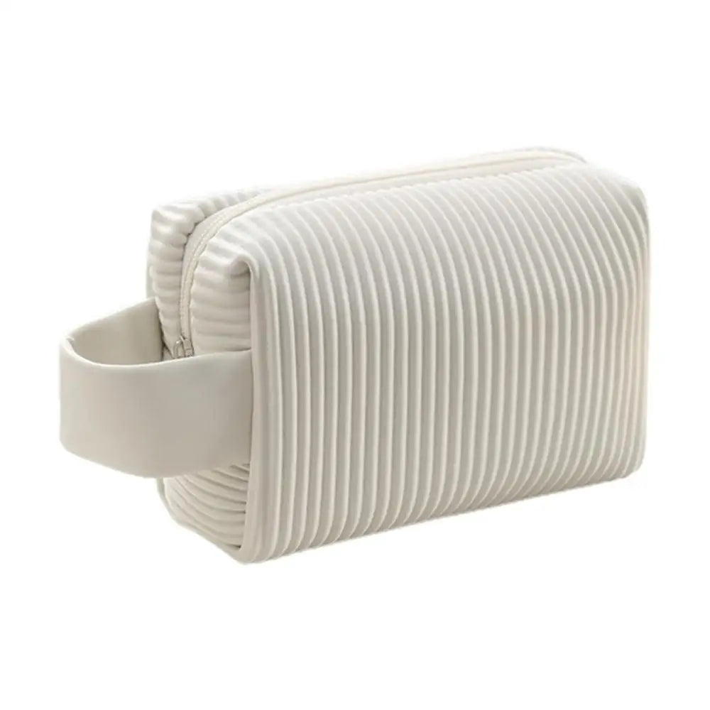 Astuccio da viaggio bianco con texture a righe, manico laterale. Design moderno, ideale per cosmetici e accessori. Accessorio elegante e funzionale.