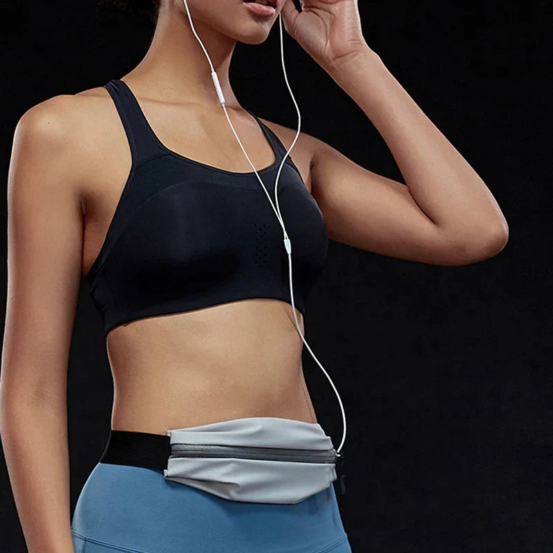 Donna in abbigliamento sportivo nero e blu, con marsupio grigio e auricolari, su sfondo nero. Fitness, accessori sportivi, moda attiva.