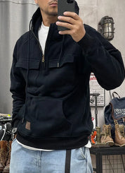 Uomo con felpa nera con cappuccio e tasche, jeans chiari, scatta selfie in negozio di abbigliamento. Felpa casual, moda uomo, abbigliamento streetwear.