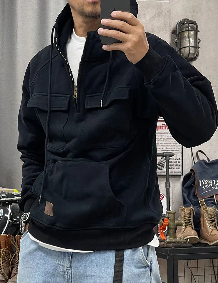 Uomo con felpa nera con cappuccio e tasche, jeans chiari, scatta selfie in negozio di abbigliamento. Felpa casual, moda uomo, abbigliamento streetwear.