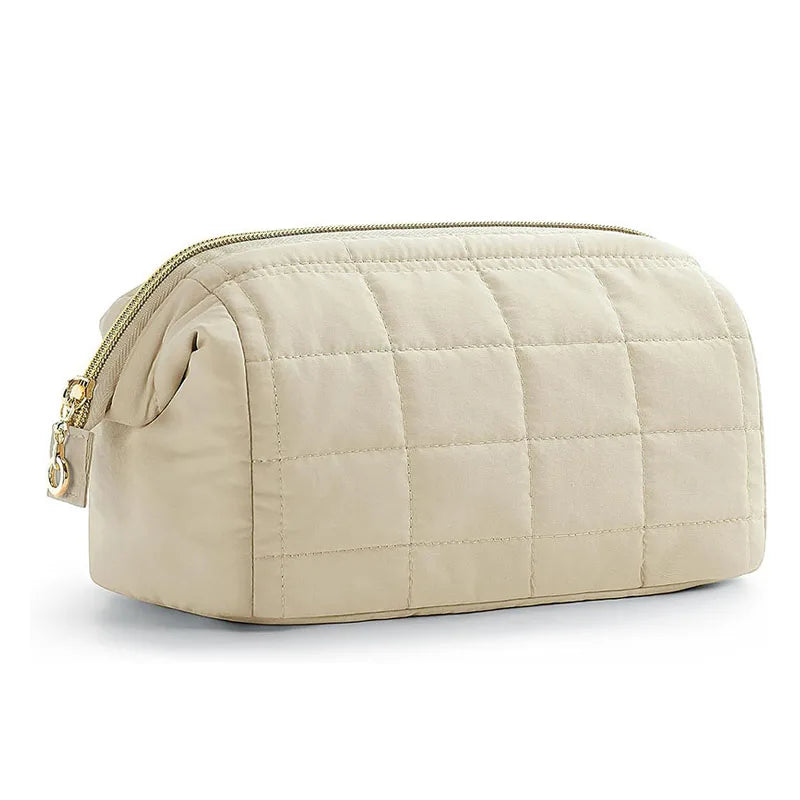 Borsa da toilette trapuntata beige con cerniera dorata, design elegante e spazioso. Accessorio da viaggio essenziale per organizzare cosmetici.