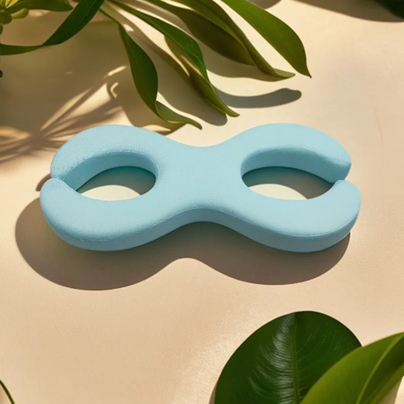 Cuscino ergonomico azzurro a forma di otto, ideale per supporto cervicale e lombare. Accessorio benessere, design moderno, materiale morbido.