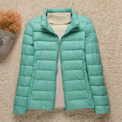 Giacca invernale trapuntata verde menta da donna su sfondo beige, con collo alto e zip frontale. Elegante e calda, ideale per la stagione fredda.