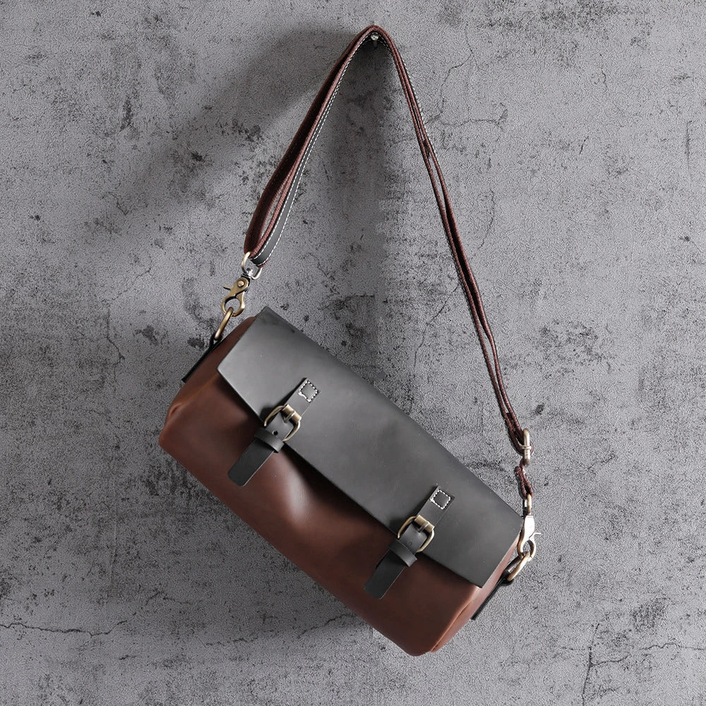 Borsa a tracolla in pelle bicolore marrone e nera, design elegante con fibbie metalliche, ideale per moda uomo e donna, accessorio di tendenza.