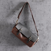 Borsa a tracolla in pelle bicolore marrone e nera, design elegante con fibbie metalliche, ideale per moda uomo e donna, accessorio di tendenza.
