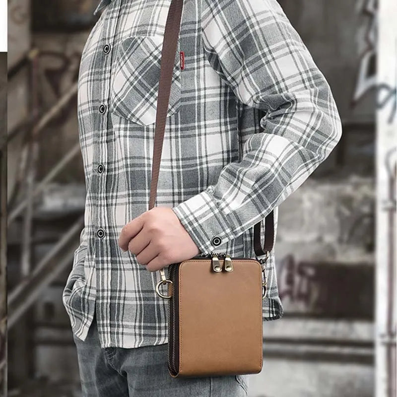 Uomo con camicia a quadri grigia indossa borsa a tracolla in pelle marrone, stile casual urbano, moda maschile, accessorio pratico e moderno.
