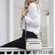Donna con borsa a tracolla bianca in pelle, dettagli marroni, indossa camicia bianca e pantaloni neri. Moda elegante, accessori femminili.
