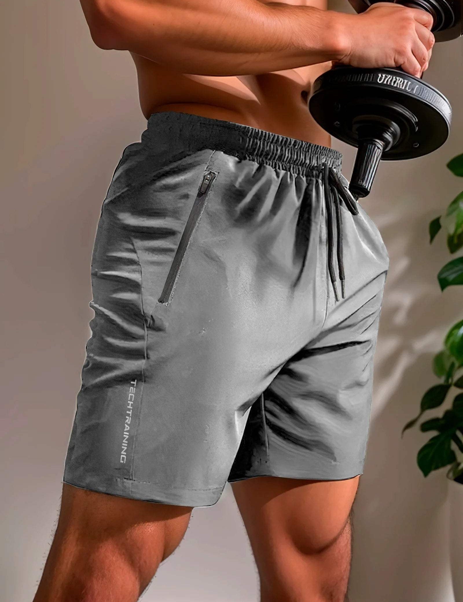 Pantaloncini sportivi grigi da uomo, con tasca con zip, indossati durante l'allenamento con manubri. Abbigliamento fitness traspirante e comodo.