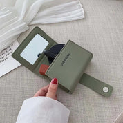 Portafoglio verde in pelle con specchio integrato, chiusura a bottone, design compatto. Accessorio moda elegante per donna.