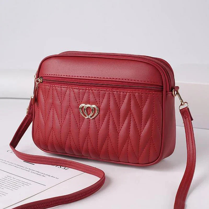 Borsa a tracolla rossa in pelle sintetica con motivo trapuntato e decorazione a cuore, ideale per moda donna, accessori eleganti e versatili.