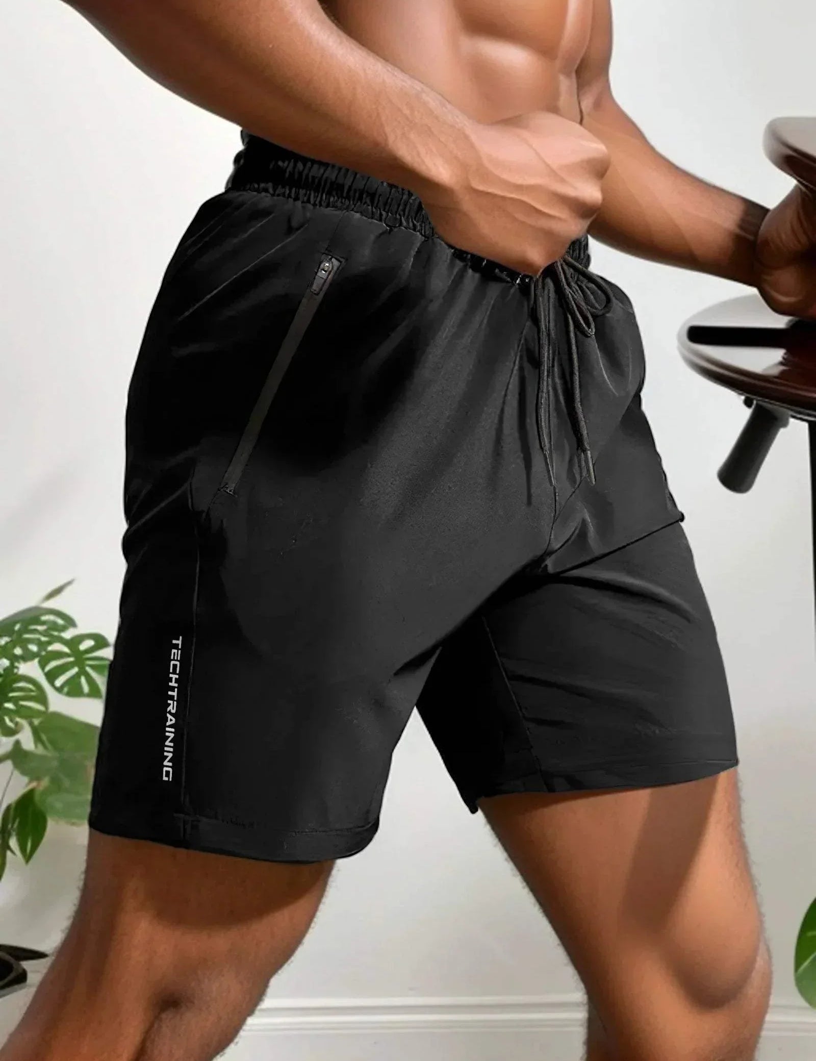 Pantaloncini sportivi neri da uomo, tessuto traspirante, con tasche con zip e laccio in vita, ideali per allenamento e fitness.