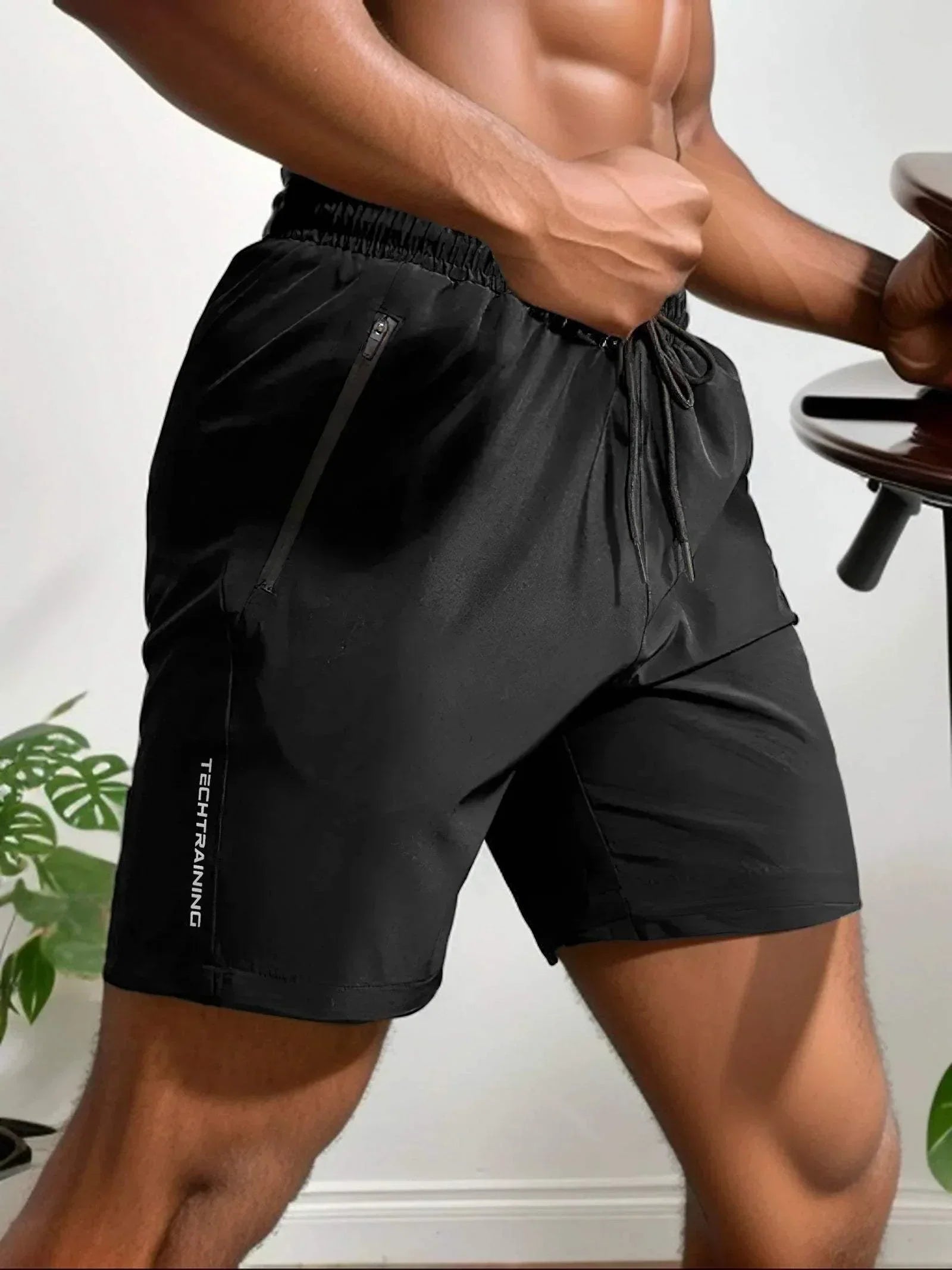 Pantaloncini sportivi neri da uomo, tessuto traspirante, con tasche con zip e laccio in vita, ideali per allenamento e fitness.