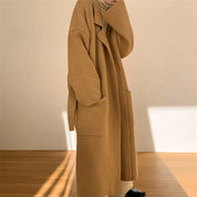 Cappotto lungo in maglia beige, design oversize, tasche frontali, moda autunno inverno, abbigliamento donna elegante e casual.
