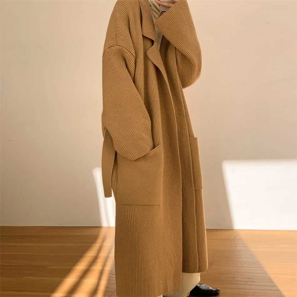 Cappotto lungo in maglia beige, design oversize, tasche frontali, moda autunno inverno, abbigliamento donna elegante e casual.