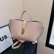 Borsa a mano in pelle beige con manici e tracolla, chiusura dorata. Design elegante e moderno, perfetta per moda donna e accessori di lusso.