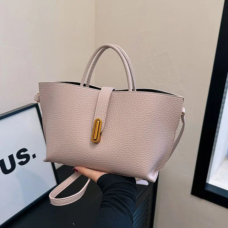 Borsa a mano in pelle beige con manici e tracolla, chiusura dorata. Design elegante e moderno, perfetta per moda donna e accessori di lusso.