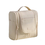 Borsa da toilette beige in tessuto, con manico superiore, tasca frontale con zip e scomparti laterali. Ideale per viaggi e organizzazione bagno.