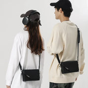 Due persone con borse a tracolla nere, abbigliamento casual, cappelli e cuffie. Moda urbana, accessori unisex, stile contemporaneo.