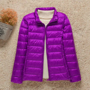 Giacca piumino viola da donna su sfondo beige, design trapuntato, ideale per l'inverno. Elegante e calda, perfetta per look casual e outdoor.