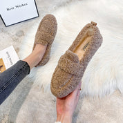 Scarpe mocassini in pelliccia sintetica marrone, design casual, su tappeto bianco. Ideali per l'inverno, comode e calde. Moda donna autunno inverno.