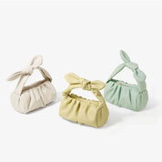 Tre borse a mano in pelle sintetica, colori pastello: beige, giallo e verde menta, con manico a fiocco. Design elegante e moderno.