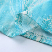 Tessuto in cotone azzurro con motivo marmorizzato, cuciture visibili. Ideale per abbigliamento estivo, artigianato e decorazioni.