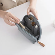 Astuccio da viaggio grigio con cerniera, contenente flaconi di cosmetici e trucchi. Organizzatore compatto per prodotti di bellezza.