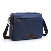 Borsa a tracolla in tela blu con tasche frontali, chiusura a zip e dettagli in pelle marrone. Design casual, ideale per uomo e donna.