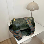Borsa a tracolla verde in pelle con motivo floreale, cinghia regolabile decorata, su tavolo moderno. Accessorio moda elegante e versatile.